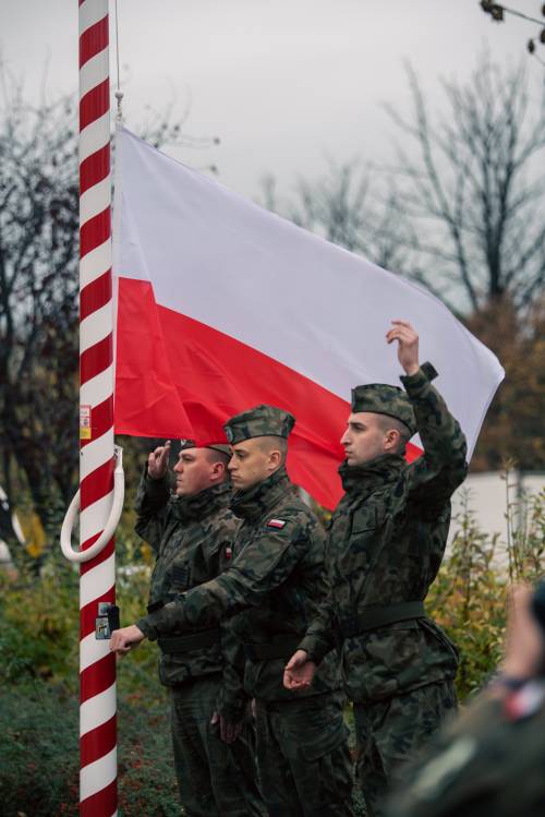 Wciągnięcie flagi Rzeczypospolitej na maszt - widać trzech żołnierzy.